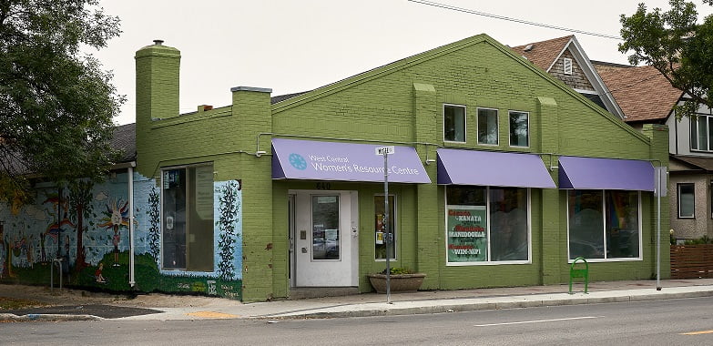 front of WCWRC building: Green building with purple awning and mural and trees on east side.